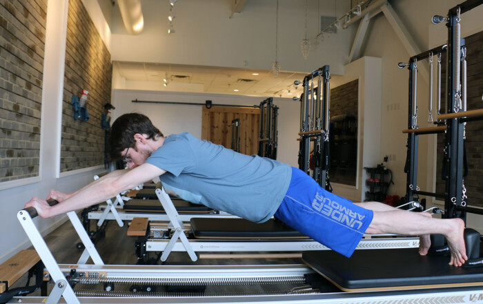 strength reformer, pilates reformer, man demonstrating reformer pilates